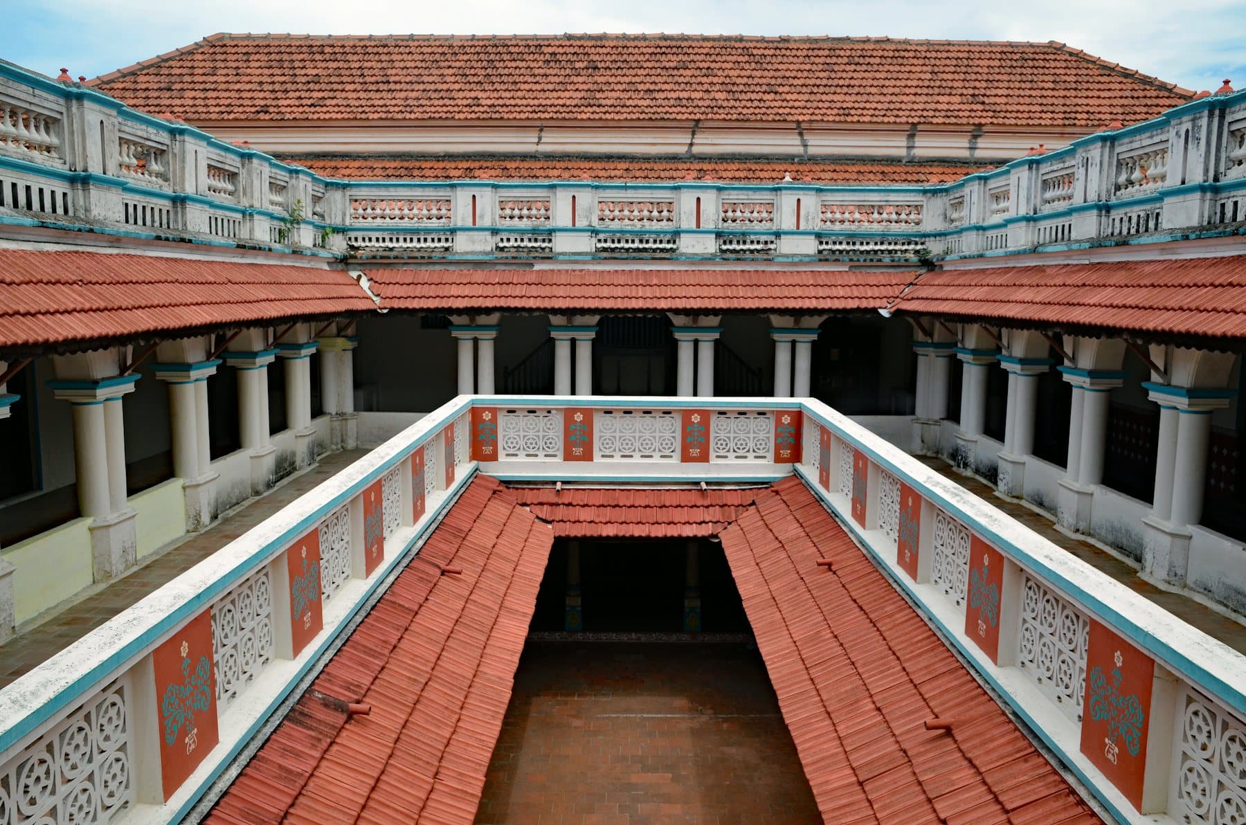 The open inner courtyard of a traditional Indian house, terracotta-tiled roofs sloping in towards it on every side